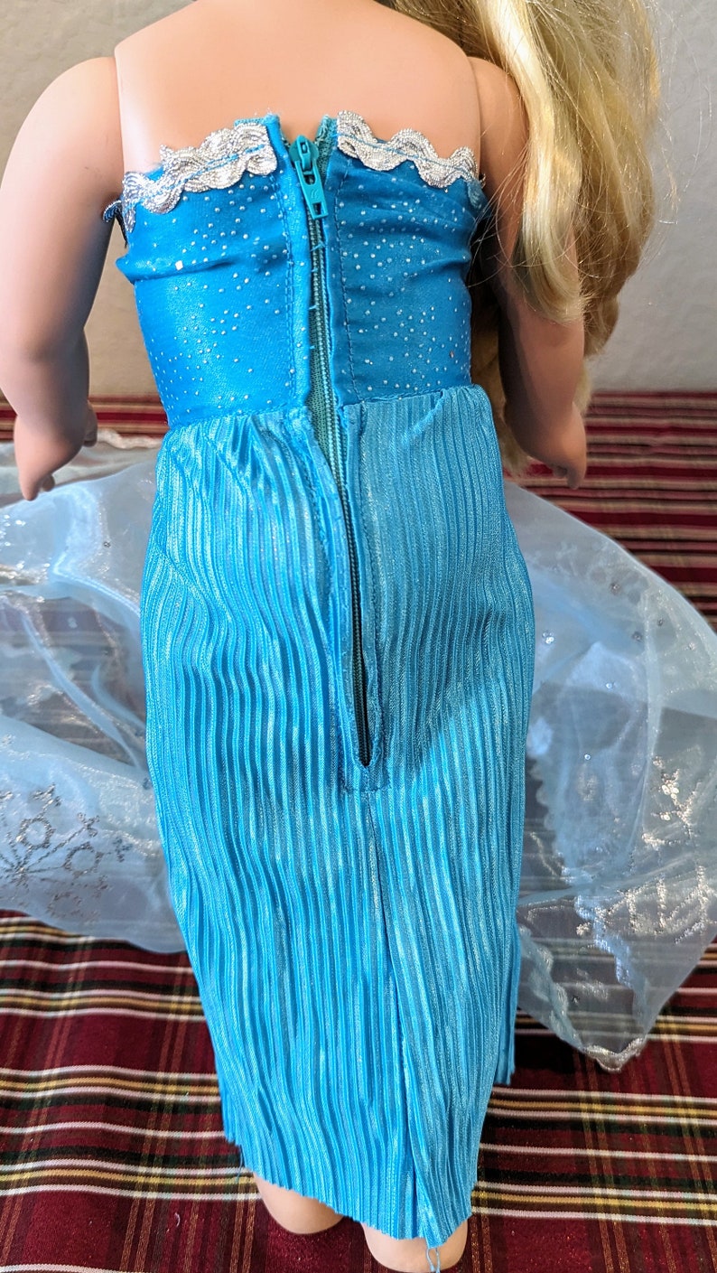 Puede incluir: Un vestido azul y plateado con una cremallera en la espalda. El vestido tiene un corpi&ntilde;o brillante y una falda plisada.