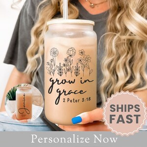 May include: A clear glass tumbler with a bamboo lid and a black floral design. The tumbler has the text "grow in grace 2 Peter 3:18" printed on it.