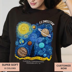 Puede incluir: Sudadera negra con una representación artística y colorida de un cielo estrellado, con planetas y un fondo azul arremolinado. El diseño incluye el texto "CC DIRECTOR" y "CLASSICAL CONVERSATIONS MISSOURI CITY, TX". La sudadera también tiene el texto "SUPER SOFT" y "8 COLORS".