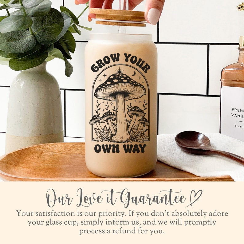 K&ouml;nnte beinhalten: Ein gefrosteter Glasbecher mit Bambusdeckel und Strohhalm. Der Becher hat eine schwarz-wei&szlig;e Illustration von Pilzen und den Text "Grow Your Own Way".