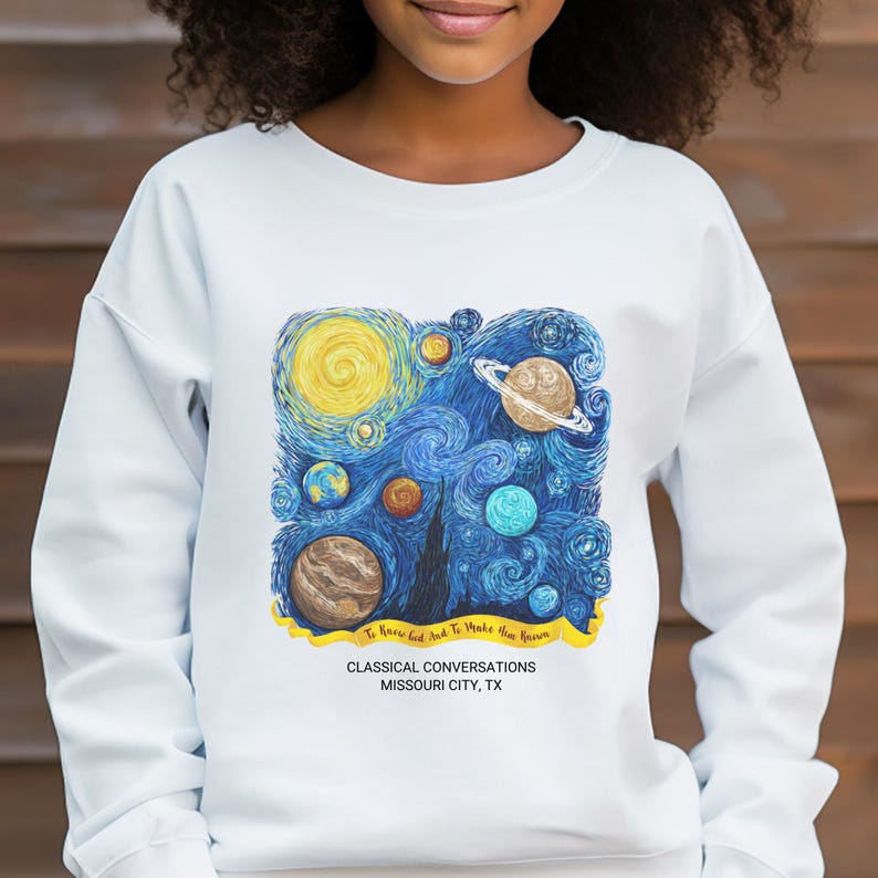 May include: A white long-sleeve sweatshirt featuring a graphic of a swirling blue starry night sky with various planets and a yellow banner. The text reads: To Know God And To Make Him Known, CLASSICAL CONVERSATIONS, MISSOURI CITY, TX.