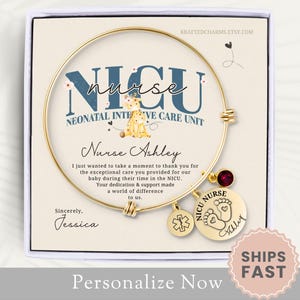 May include: Gold bangle bracelet with charms, including a red rhinestone, a star of life charm, and a charm with the words "NICU Nurse" and a footprint design. The bracelet is displayed in a white box with a message thanking a NICU nurse for their care. The message reads "I just wanted to take a moment to thank you for the exceptional care you provided for our baby during their time in the NICU. Your dedication & support made a world of difference to us. Sincerely, Jessica."