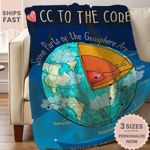 May include: A blue fleece blanket with a colorful illustration of the Earth and the text "CC to the Core" and "Some Parts of the Geosphere Are." The illustration shows the Earth's layers, including the core, mantle, crust, atmosphere, biosphere, and hydrosphere.