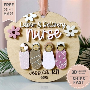 May include: A wooden ornament with the words "Labor & Delivery Nurse" and the name "Jessica, RN 2025". The ornament features four baby figures and decorative flowers. A pink ribbon is attached for hanging.
