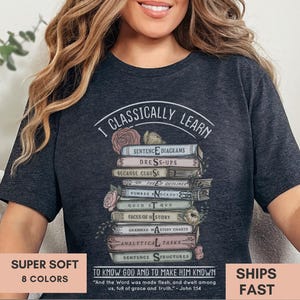 May include: A dark grey t-shirt with a graphic of a stack of books with the text "I Classically Learn" and a quote from the Bible: "To know God and to make Him known."  "And the Word was made flesh, and dwelt among us, full of grace and truth." -John 1:14