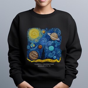 May include: A black crewneck sweatshirt featuring a graphic print of a swirling starry night sky with various planets. A yellow banner contains the text To Know God And To Make Him Known, with Classical Conversations Missouri City, TX below.
