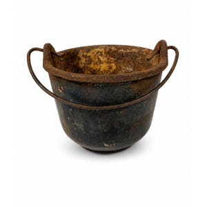 May include: A weathered cast iron pot with a dark, oxidized exterior and a heavily rusted, textured interior. The vessel features a wide, circular rim and two curved metal handles attached to the sides, showing significant signs of age and wear.