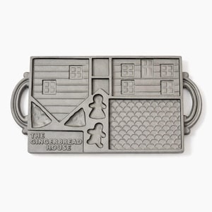 May include: A rectangular, gray metal baking mold with a gingerbread house design. The mold features house sections, gingerbread man shapes, and the text "THE GINGERBREAD HOUSE". Includes two rounded handles on each side.
