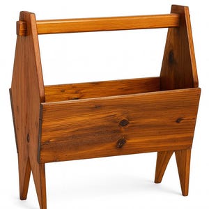 May include: A wooden magazine rack with a handle. The rack is made of stained wood with a natural finish. It has a rectangular body with angled legs and a handle at the top. The wood grain is visible.