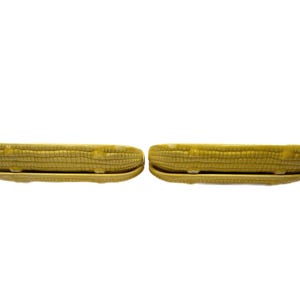 May include: Two yellow ceramic serving dishes shaped like ears of corn. The dishes are designed to hold corn on the cob.
