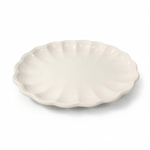 May include: Off-white ceramic serving platter with a scalloped edge. The oval-shaped dish has a smooth, glossy surface and a gently curved rim. The plate is designed for serving food.