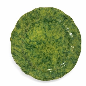 May include: A round, green ceramic plate with a wavy edge. The plate has a mottled pattern of light and dark green, creating a textured appearance. The plate is suitable for serving food.