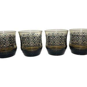 May include: Set of four clear glass tumblers with a black swirling pattern. The glasses are slightly flared at the top and have a rounded bottom.