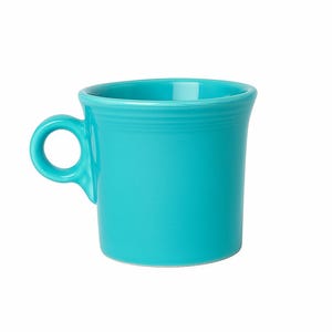 Puede incluir: Una taza de cerámica turquesa con un asa redondeada. La taza tiene forma cilíndrica con un borde ligeramente ensanchado. La taza es de color turquesa brillante y sólido, sobre un fondo blanco.