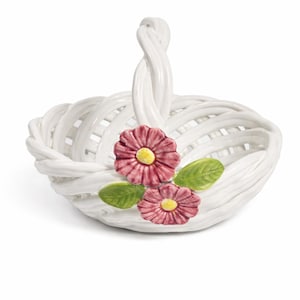 May include: White ceramic basket with a woven design and a twisted handle. The basket is decorated with two pink flowers with yellow centers and green leaves. A decorative piece for the home.