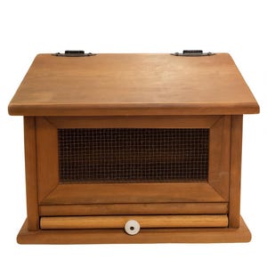 以下が含まれることがあります： 傾斜した上部とメッシュのフロントパネルを備えた木製のパンボックス。ボックスには、白いノブが付いた小さな引き出しがあります。木材は暖かく自然な仕上がりで、ヒンジは濃い色の金属です。