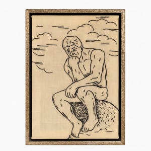 Puede incluir: Una obra de arte enmarcada que presenta un dibujo lineal negro de una figura sentada en una pose contemplativa, con la barbilla apoyada en la mano. La obra de arte está sobre un fondo claro con contornos de nubes y enmarcada en un marco dorado.