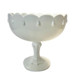 May include: White ceramic pedestal bowl with a scalloped rim and teardrop accents. The bowl is on a pedestal base.