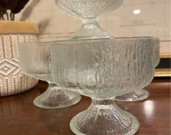 May include: Set of four clear glass dessert bowls with a textured, ribbed design. The bowls have a footed base.