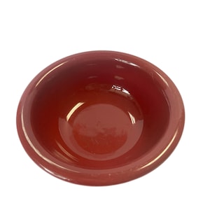 May include: A red ceramic bowl with a smooth, glossy finish. The bowl is round and shallow, with a slightly flared rim.
