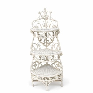 May include: A white, three-tiered wicker corner shelf with decorative scrollwork and a crown-like top. The shelves are triangular, and the piece stands on three legs. The overall design is ornate and vintage-inspired, suitable for displaying plants or decor.