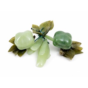 May include: A jade sculpture of a cluster of fruit and leaves. The sculpture features light green and dark green fruit, with detailed leaves in shades of green and brown. The fruit is connected with green wire.