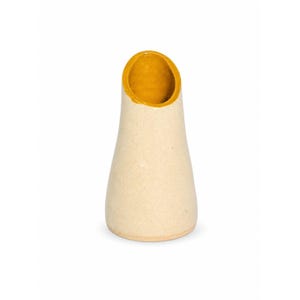 Può includere: Un vaso in ceramica dalla forma conica affusolata con un'ampia apertura inclinata. L'esterno presenta una finitura opaca color bianco sporco con macchioline, mentre l'interno del bordo è smaltato in un vivace colore giallo senape.