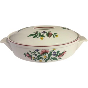 Puede incluir: Fuente ovalada con tapa, blanca, decorada con un motivo floral. Flores rosas, moradas y amarillas con hojas verdes. Un ribete rojo acentúa el borde de la fuente y la tapa.