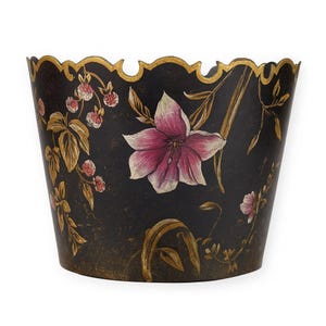 May include: A black decorative container with a scalloped gold rim. The container is adorned with hand-painted floral designs, including a large pink and white flower and smaller pink blossoms.
