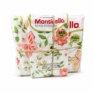 May include: Three packaged pillowcases tied with twine. The pillowcases feature a floral and butterfly pattern in shades of pink, green, and yellow on a white background. The packaging includes the brand name "Monticello."