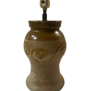 May include: A brown and beige ceramic table lamp with a swirl design. The lamp has a simple, classic design and would look great in a variety of settings.