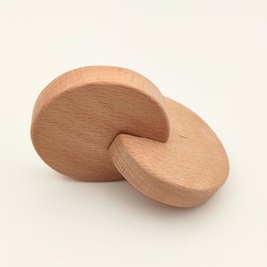 May include: Two wooden circles, one partially overlapping the other, creating a unique shape. The circles are made of light brown wood and have a smooth, polished finish.
