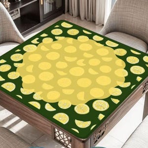 Pode incluir: Uma toalha de mesa quadrada com um design de lim&atilde;o. A capa tem uma borda verde escura com fatias de lim&atilde;o e um centro amarelo cheio de formas de lim&atilde;o. A mesa &eacute; de madeira e tem entalhes decorativos.
