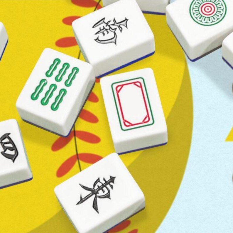 May include: A close-up of several white Mahjong tiles with various symbols and markings in green, red, and black. The tiles are arranged on a yellow and blue patterned surface, suggesting a game in progress.