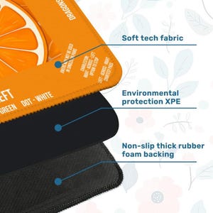 K&ouml;nnte beinhalten: Nahaufnahme eines mehrschichtigen Mauspads mit einem orange-wei&szlig;en Design. Das Mousepad verf&uuml;gt &uuml;ber ein weiches Tech-Gewebe, einen Umweltschutz XPE und eine rutschfeste, dicke Schaumstoffr&uuml;cken. Text enth&auml;lt "GREEN DOT-WHITE".