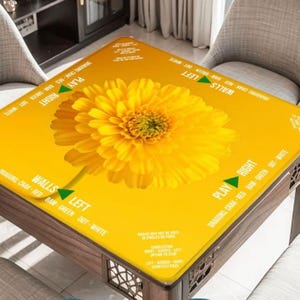 Puede incluir: Una mesa cuadrada con una superficie amarilla brillante con una gran margarita amarilla. La mesa tiene texto alrededor de los bordes, incluyendo "PLAY RIGHT" y "WALLS LEFT". La mesa es de madera y tiene un dise&ntilde;o decorativo.