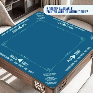 May include: A square blue Mahjong table mat featuring white printed text and directional arrows. The mat displays game instructions, including 'PLAY RIGHT', 'WALLS LEFT', and lists of tile types like 'DRAGONS', 'CRAK', 'RED', 'BAM', 'GREEN', 'DOT', 'WHITE'.