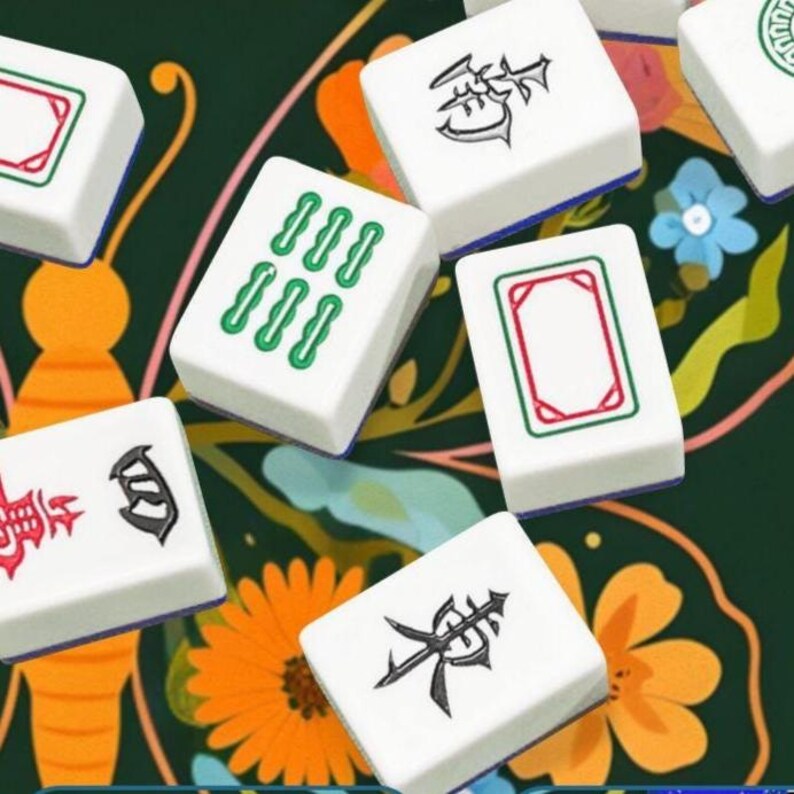 Puede incluir: Primer plano de fichas de Mahjong blancas con s&iacute;mbolos verdes, rojos y negros. Las fichas est&aacute;n dispuestas sobre un fondo verde oscuro con dise&ntilde;os florales y de mariposas. La imagen muestra los detalles de las piezas del juego.