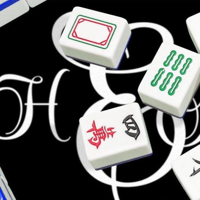 May include: Three white rectangular Mahjong tiles with distinct markings. One tile features a green and red rectangular border, another displays six green vertical symbols, and the third shows a red Chinese character and a black symbol.