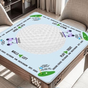 May include: A square game table with a light blue surface featuring a large white golf ball design in the center. The table has text and illustrations around the edges, including the words "PLAY RIGHT" and "WALLS LEFT". The table is made of wood.
