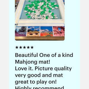 May include: A Mahjong game set with green tiles scattered on a light blue mat, framed by a white wooden border. The mat rests on a decorative surface with landscape images. The text on the image says: Beautiful One of a kind Mahjong mat!