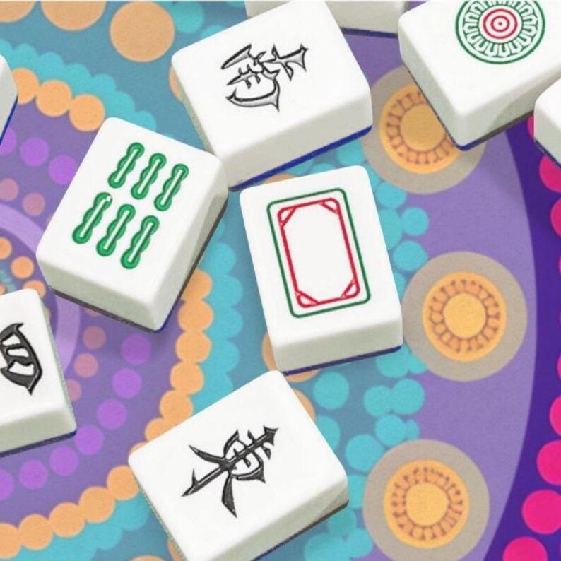 Puede incluir: Un conjunto de fichas de Mahjong blancas con varios s&iacute;mbolos y marcas en verde y negro. Las fichas est&aacute;n dispuestas sobre una superficie estampada colorida con tonos morados, naranjas y azules. Las piezas del juego son rectangulares y tienen una est&eacute;tica limpia y moderna.