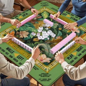 May include: A Mahjong game in progress, played on a green table with a jungle pattern. The set includes pink and white tiles. The table has text that says "WALLS LEFT" and "PLAY RIGHT". The table is approximately 120 cm x 120 cm.