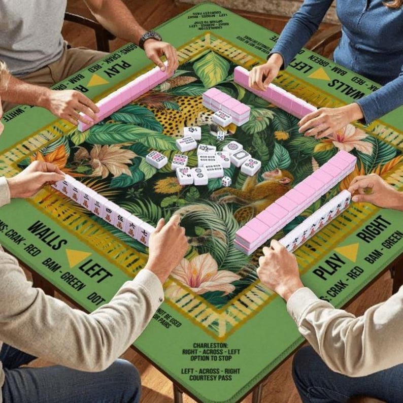 May include: A Mahjong game in progress, played on a green table with a jungle pattern. The set includes pink and white tiles. The table has text that says "WALLS LEFT" and "PLAY RIGHT". The table is approximately 120 cm x 120 cm.