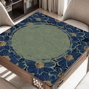 May include: Square wooden table with a floral design. The table's surface features a pattern of blue flowers with yellow centers against a dark blue background. A lighter green circle in the center has a faded floral design.