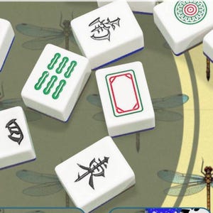 May include: A collection of white Mahjong tiles with various symbols and markings in green, red, and black. The tiles are arranged on a green surface with dragonfly illustrations. The tiles have blue edges.