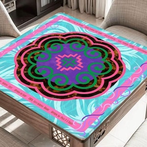 May include: A square table cover with a central floral design in purple, green, and brown, surrounded by a pink and blue border. The cover has text that reads "THIS LIFE ACROSS RIGHT OPTION TO PASS 1-3 TILES".