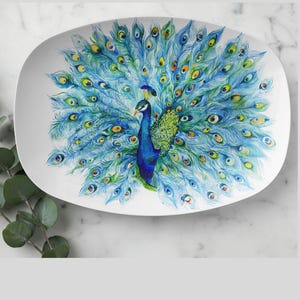 May include: White oval serving platter featuring a vibrant peacock design. The peacock is depicted with its tail feathers fully fanned out, showcasing shades of blue, green, and yellow. The platter is ideal for serving appetizers or entrees.