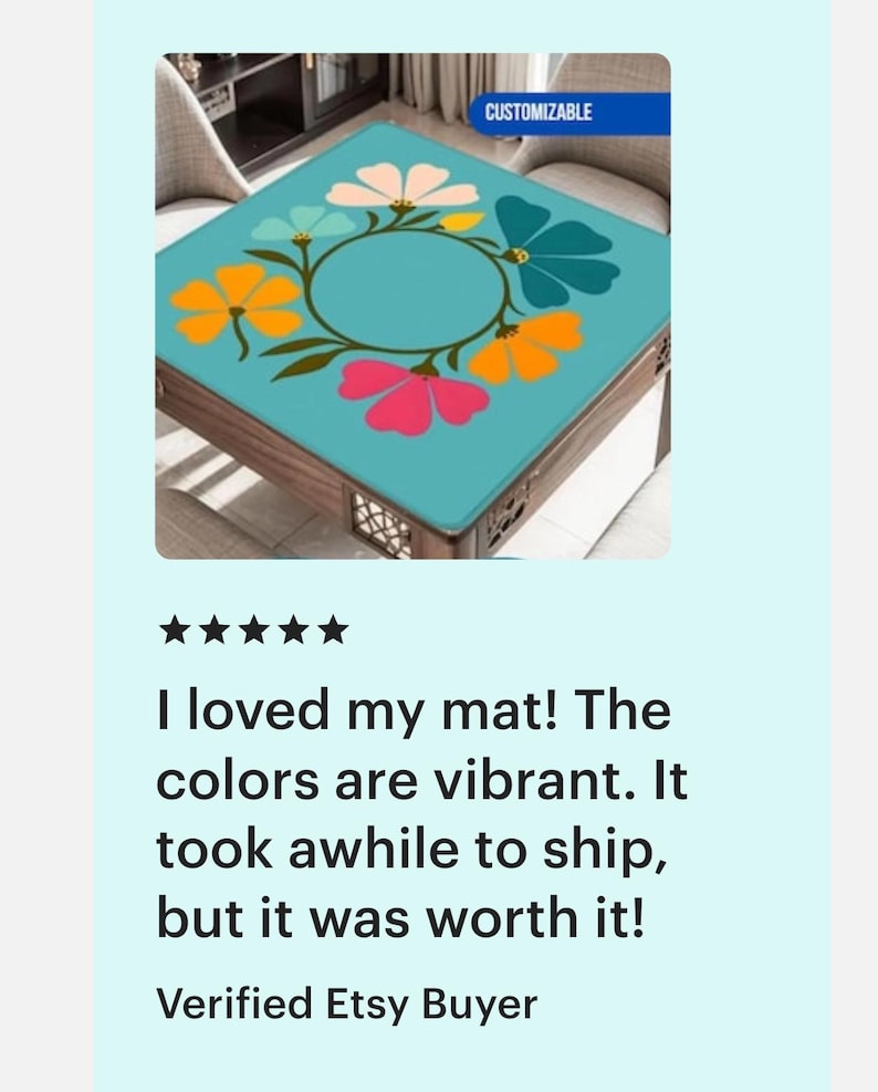 May include: A square table mat with a teal background and a floral design in pink, orange, yellow, and teal. The mat is customizable, as indicated by the text in the upper right corner.