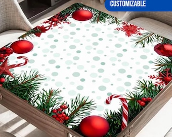 May include: A square tablecloth featuring a white center with light green polka dots, bordered by a festive pattern of green pine branches, red ornaments, red berries, red star-shaped decorations, and red and white striped candy canes.